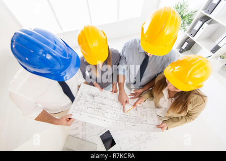 Top view of four successful architect checking the architectural plans. Stock Photo