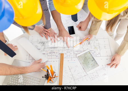 Top view of four successful architect checking the architectural plans. Stock Photo