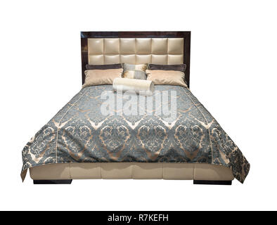 Luxury gray beige modern bed furniture with patterned bedclothes with leather upholstery headboard. Soft velour fabric bedclothes. Classic modern bed standing at an angle on isolated background Stock Photo