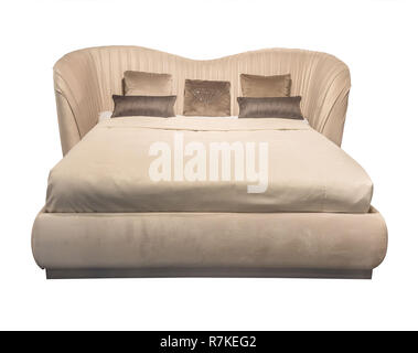 Luxury beige modern bed furniture with patterned pillows with rhinestones and with leather upholstery headboard . Soft velour fabric bedclothes. Classic modern furniture on isolated background Stock Photo