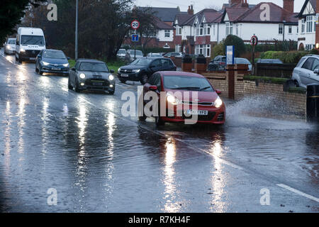 Chester, Cheshire, UK. 10th December 2018. Traffic navigates a flooded road after a heavy rain shower causes a flash flood on Newton Lane in the suburbs of the city. Credit: Andrew Paterson/Alamy Live News Stock Photo