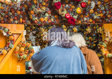 Winchester, Hampshire, UK. 10th Dec 2018. Crowds flock to Winchester Christmas Market while the sun is out. Visitors looking at scented spice fruit products for sale on market stall. Women looking at scented spice fruit products on stall. Credit: Carolyn Jenkins/Alamy Live News Stock Photo