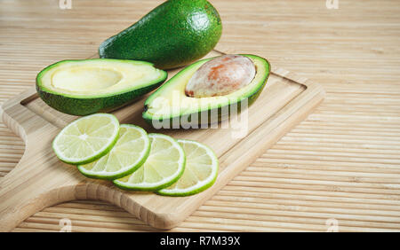 Ripe avocado and lime slices on wooden background Stock Photo