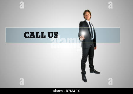 Businessman touching - Call us - navigation bar on a virtual screen with his finger from behind in a conceptual image. Stock Photo