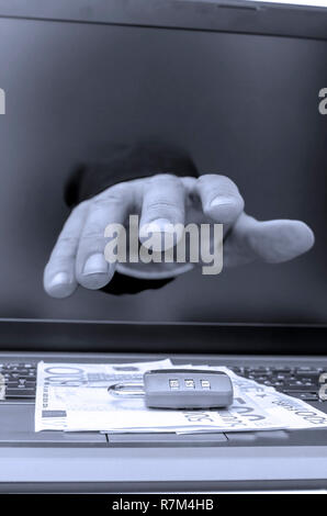 Hand coming out of computer monitor trying to steal ones money. Stock Photo