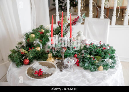 Festive table setting among winter decorations and white candles. Top view, flat lay. The concept of a Christmas or Thanksgiving family dinner. Stock Photo