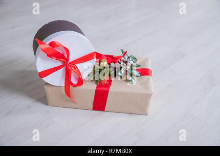Christmas Presents and Ornaments on Wooden Background.Wrapped Christmas presents shot on warm wooden floor.Presents in craft and colored paper decorated with red ribbon bows and snowflakes. Christmas and other holidays concept. Stock Photo