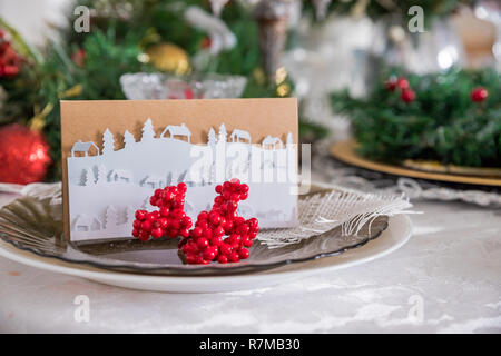 Beautiful Christmas holiday backround with Red ornaments, holly berry, bow and christmas decorations in vintage style. Christmas table decor.Greeting card.Christmas Family Dinner Table Concept.Table setting Stock Photo