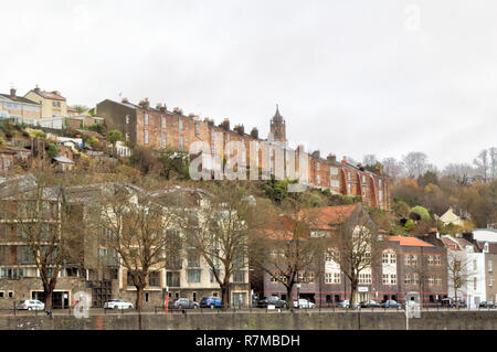Brick made terrace houses over a hill next to a street with a boulevard with parked cars during a cloudy day in Bristol, United Kingdom Stock Photo