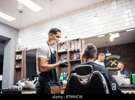A man client talking to haidresser and hairstylist in barber shop. Stock Photo