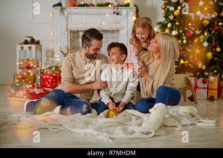 Happy family sitting near Christmas tree Stock Photo
