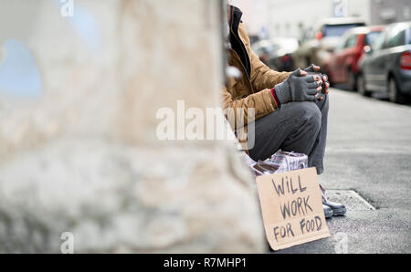 Homeless beggar man sitting outdoors in city asking for money donation. Copy space. Stock Photo