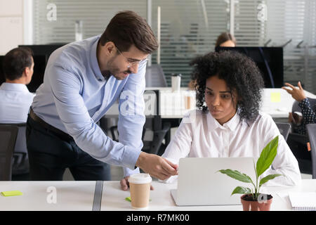 Serious verifier checking subordinate work on laptop Stock Photo