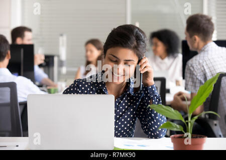 Smiling Indian female employee talking on phone Stock Photo