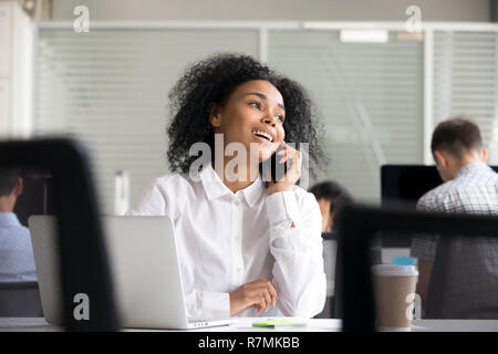 Smiling African American woman talking on phone at workplace Stock Photo