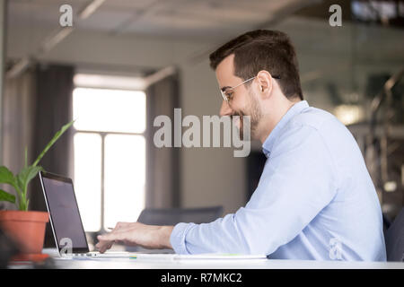 Smiling confident man in glasses using laptop, typing Stock Photo