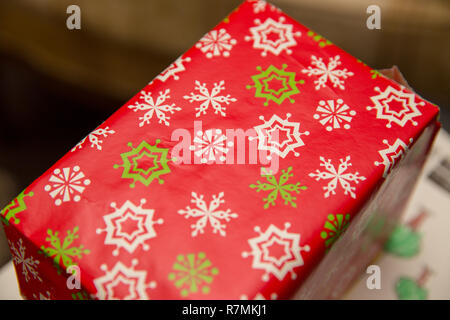 Rectangular box wrapped in red, white, and green wrapping paper. Stock Photo