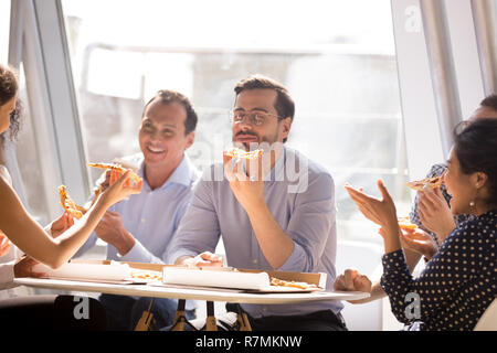 Businessman enjoying pizza with friendly colleagues during break Stock Photo