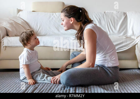 Cute small boy with Down syndrome playing with mother in home Stock Photo