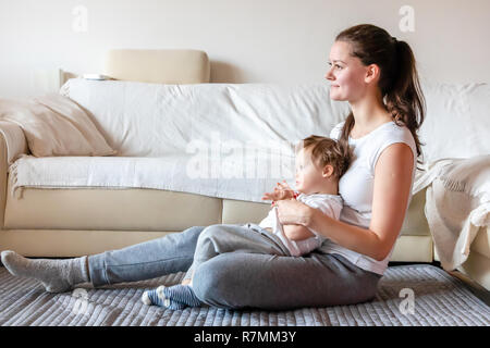 Cute small boy with Down syndrome playing with mother in home Stock Photo
