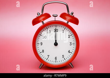 Red vintage alarm clock on pink pastel background. Bright stylized colors. Stock Photo