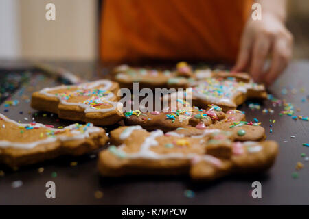 Christmas bakery. Friends decorating freshly baked gingerbread cookies with icing and confectionery mastic, view from above. Festive food, family culi Stock Photo