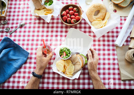 Above view closeup of unrecognizable man sitting at picnic table eating healthy snacks, copy space Stock Photo