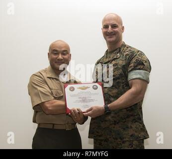 U.S. Marine Corps Col. Daniel L. Shipley, Marine Aircraft Group (MAG) 12 commanding officer, right, presents U.S. Navy Lt. Cmdr. Philip N. Park a certificate for qualifying as a Fleet Marine Force Officer for his outstanding commitment to his duty as the MAG 12 head chaplain at Marine Corps Air Station Iwakuni, Japan, March 21, 2017. The ceremony recognized Park for helping Marines by providing religious, financial and family counseling services. Stock Photo