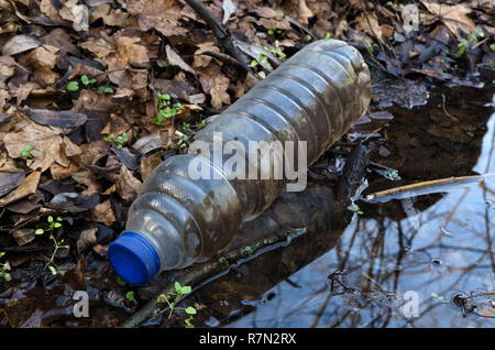 An empty plastic bottle thrown into the water in the nature. Environmental pollution.