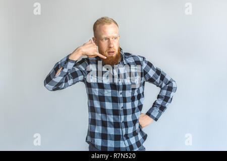 Freestyle. Mature man standing isolated on grey showing call gesture talking thoughtful Stock Photo