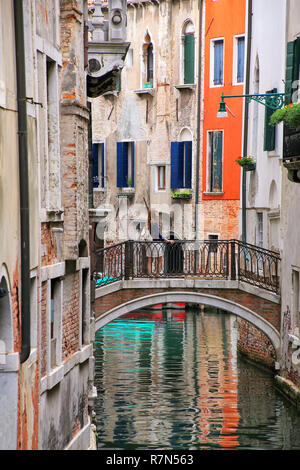 Houses along narrow canal connected by a stone bridge in Venice, Italy. Venice is situated across a group of 117 small islands that are separated by c Stock Photo