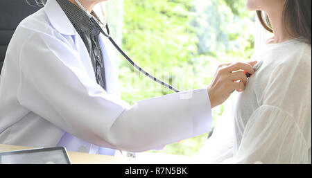 Doctor using stethoscope for examining patient  in his office at Hospitals Stock Photo