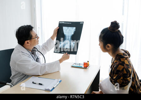 The doctor is explaining about the brain X-ray results to a female patient in his office at Hospitals Stock Photo