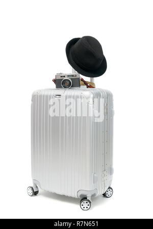 Aluminum Travel Suitcase with vintage camera and black hat isolated on white background, travel concept Stock Photo