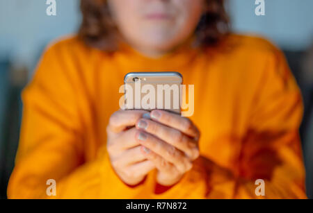 Close up of teenager or adult woman playing online and sending text on smart phone with a colorful background light from the screen in Mobile addictio Stock Photo
