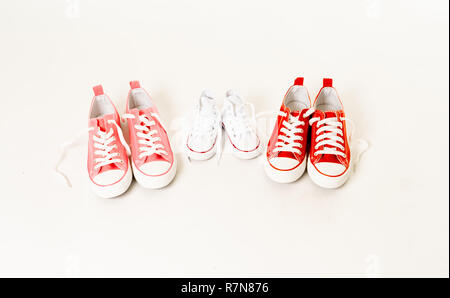 Conceptual image of gumshoes sneakers of two mothers and son daughter isolated on white background copy space in modern family togetherness Parenting  Stock Photo