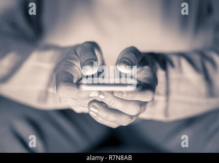 Close up of teenager or adult woman playing online and sending text on smart phone with a colorful background light from the screen in Mobile addictio Stock Photo