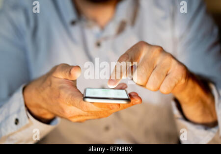 Close up of teenager or adult man playing online and sending text on smart phone with a colorful background light from the screen in Mobile addiction  Stock Photo