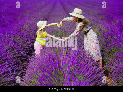 trendy mother and child making heart with hands against lavender field of Provence, France. South of France perfect place for agritourism and also new Stock Photo