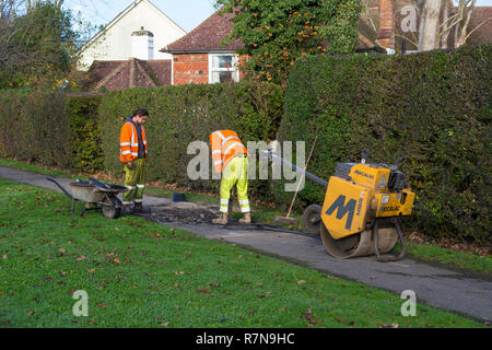 Roadside workers drilling into tarmac path, ashford, uk Stock Photo