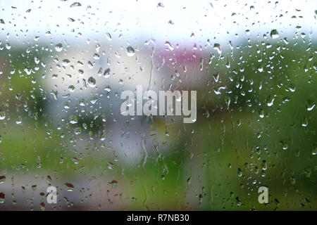 Dull landscape with many raindrops through house window on rainy autumn day Stock Photo