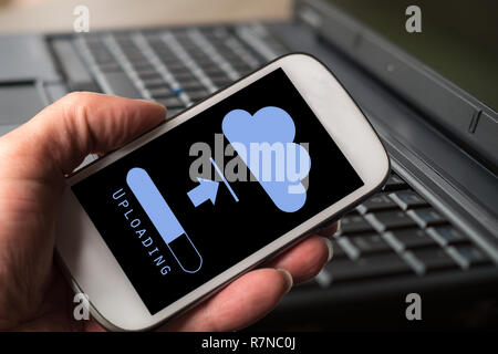 Hand with smartphone. Using smartphone to upload data. Cloud computing concept. Save data in cloud storage. Stock Photo