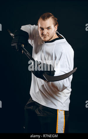 Hockey player shoots the puck and attacks, isolated over black background. Stock Photo