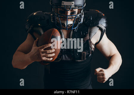 Football player wearing protective gear and holding helmet Stock Photo