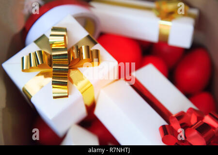 packages and red hearts in brown bag (present boxes with gold and red ribbons) as holiday gift boxes for festive giving seasons. Happiness Sharing, Fe Stock Photo