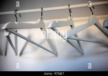 Empty white coat hangers on white rail in white cupboard Stock Photo