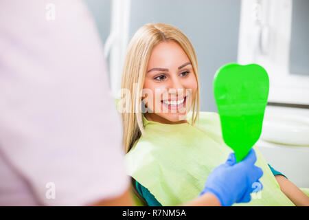 Young woman looking at her teeth after successful dental treatment. Stock Photo