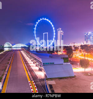 Singapore, 31 Oct 2018: a night viesw of the Formula One Singapore Grand Prix circuit stands in front of the Marina Bay area and the Flyer Wheel. Stock Photo