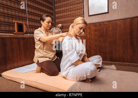 Professional female masseuse massaging her clients shoulders Stock Photo