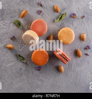 Appetizing macaroons on a textured background with almond nuts. View from above. Square. Stock Photo